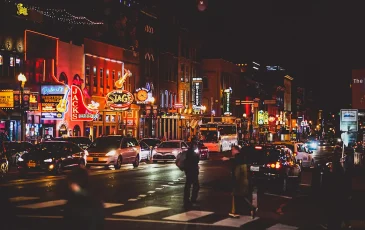 View of Lower Broadway, downtown Nashville, TN at night with neon signs brightly lit.
